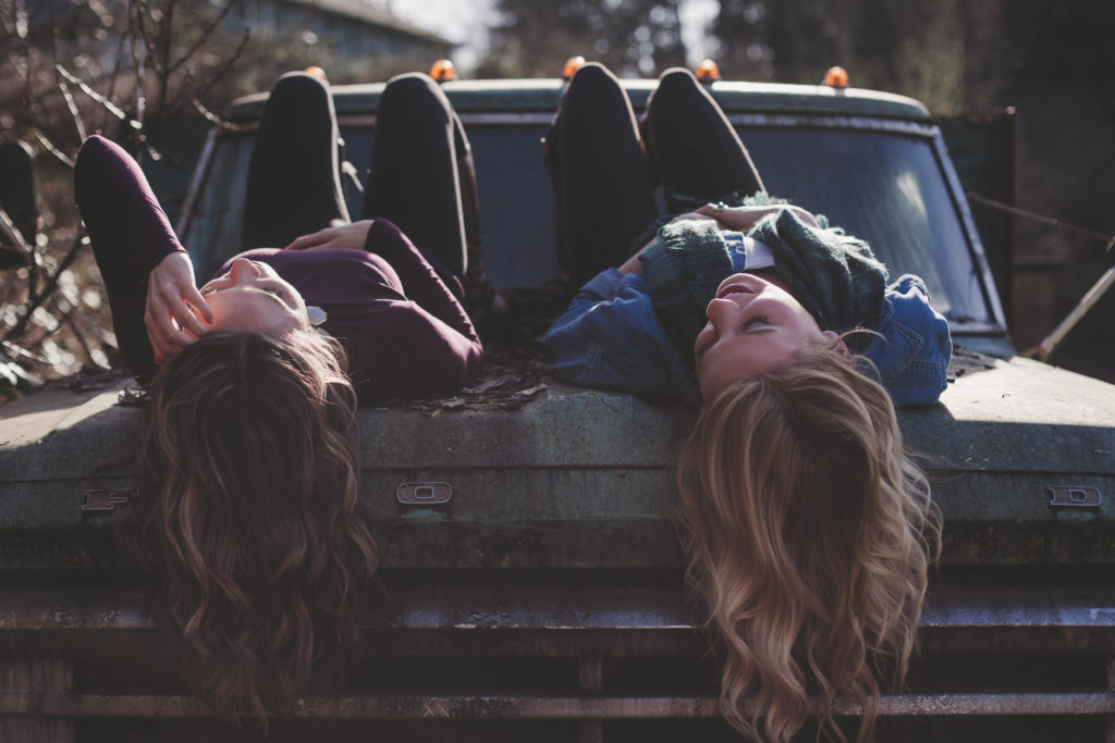 girls laying on car